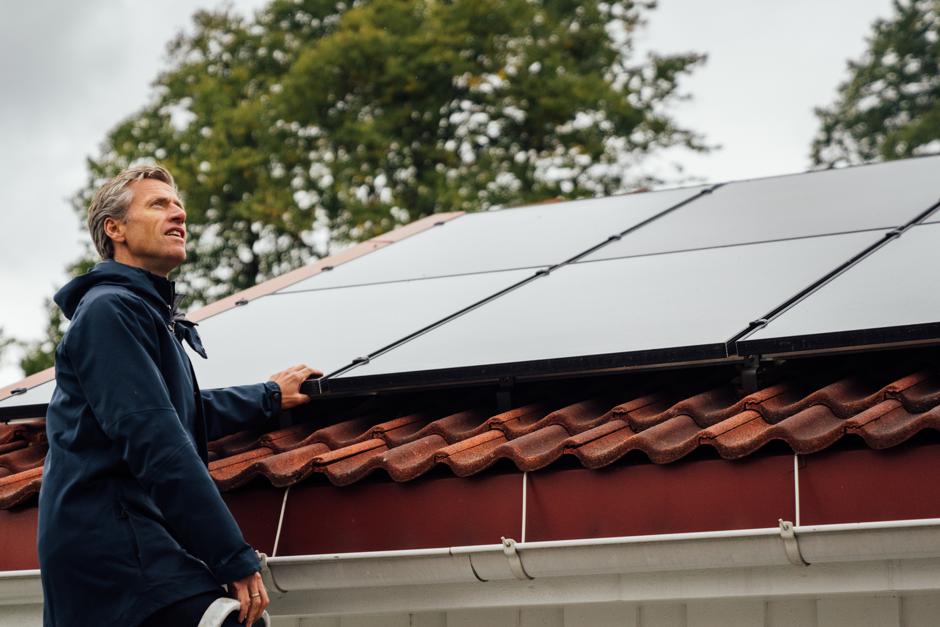 Eine Privatperson zeigt eine Solaranlage auf dem Dach ihres Hauses.